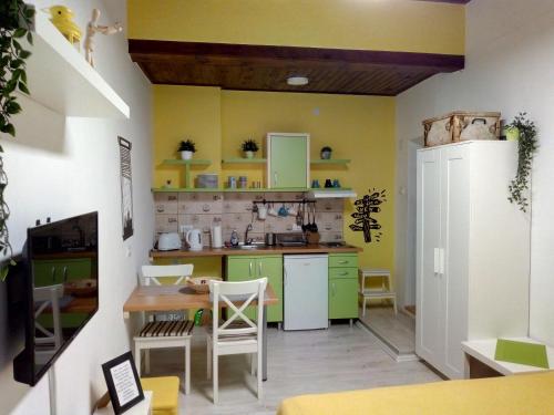 a kitchen with yellow and green cabinets and a table at Studio Jolie in Novi Sad