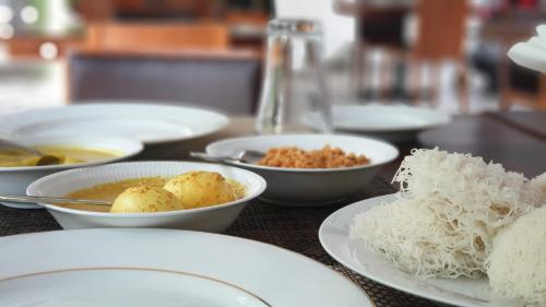 a table with white plates and bowls of food at Royal Tusker Hotel in Udawalawe