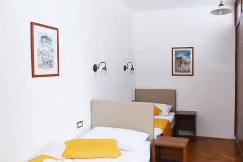 two beds in a room with white walls at Guesthouse KUBUS in Ljubljana