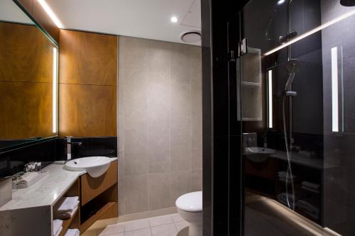 a bathroom with two sinks and a toilet and a shower at Mercure Sydney Liverpool in Liverpool