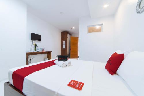 a bedroom with a large white bed with red pillows at RedDoorz Plus @ San Roque Roxas City in Roxas City