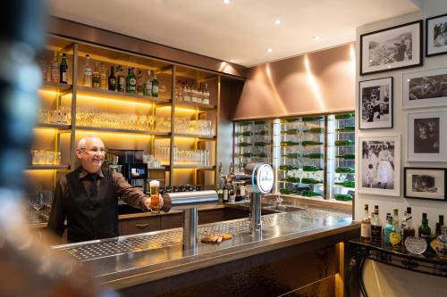 a man standing at a bar with a glass of wine at Parkhotel Herne in Herne