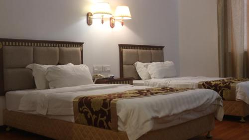 two beds in a hotel room with white walls at Beach Garden Hotel in Dili
