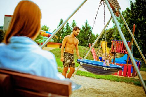 a young man on a swing set in a park at Apartman Szanyi in Bük