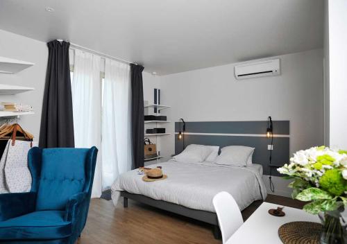 ein Schlafzimmer mit einem Bett und einem blauen Stuhl in der Unterkunft CLOS DES THERMES A JONZAC in Jonzac