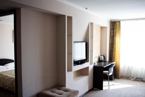 a hotel room with a bed and a tv and a desk at Orbita Hotel in Minsk