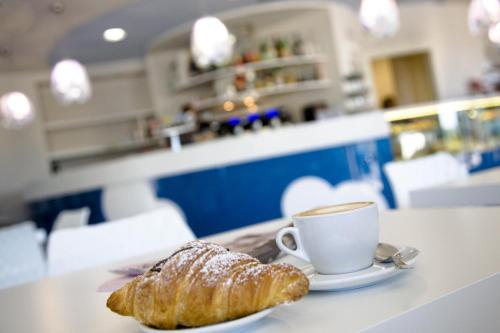 a cup of coffee and a croissant on a table at La Perla in Camerano