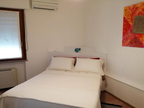 een kleine slaapkamer met een wit bed met 2 kussens bij Casa Pinna in Càbras