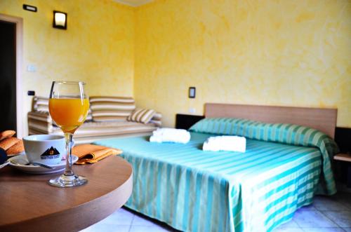 una camera con un letto e un bicchiere di vino su un tavolo di Hotel Onda Bleu a Botricello