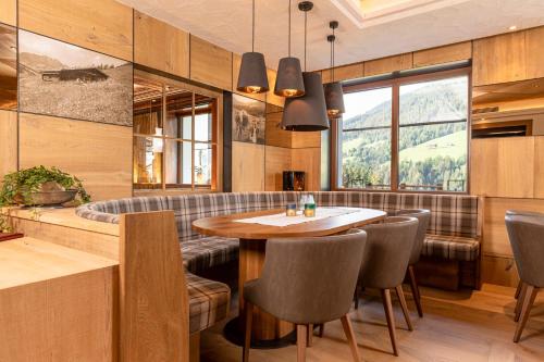 アルプバッハにあるAlpbacherhof Mountain & Spa Resortのテーブルと椅子と窓のあるダイニングルーム