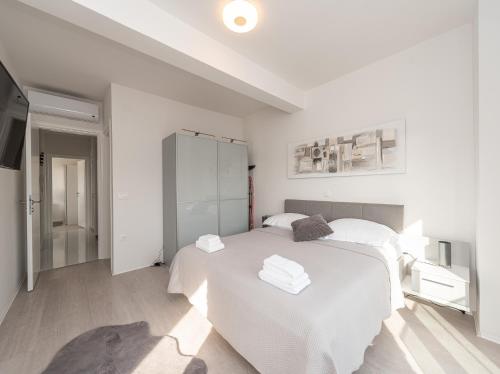 a white bedroom with a bed and a tv at Villa Contessa in Privlaka