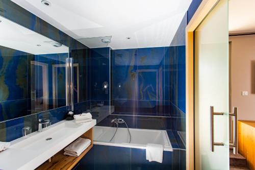 a bathroom with blue tiled walls and a tub at Hôtel Le Rapp in Colmar