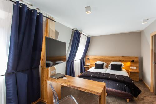 a bedroom with a bed and a desk with a television at Hôtel Le Rapp in Colmar