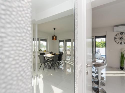 a dining room with a table and a clock on the wall at Villa Contessa in Privlaka