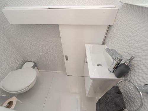 a white bathroom with a toilet and a sink at Villa Contessa in Privlaka