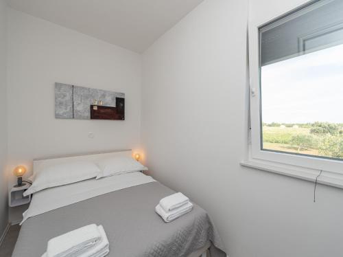 a white bedroom with a bed and a window at Villa Contessa in Privlaka