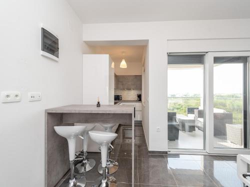 a kitchen with white walls and a counter with white stools at Villa Contessa in Privlaka