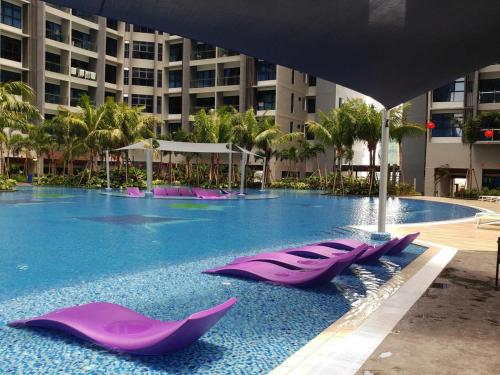a large swimming pool with purple loungers in front of a building at Mykey Atlantis D-08-05 Melaka City Swimming pool close in Malacca