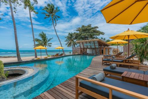 a pool at a resort with chairs and umbrellas at Princess Paradise Koh Phangan in Baan Khai
