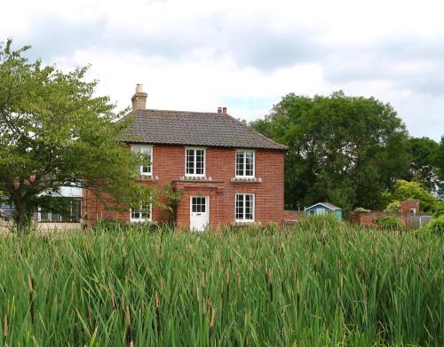 an old red brick house in a field of tall grass at Partridge Lodge Self Catering houses in Woodbridge