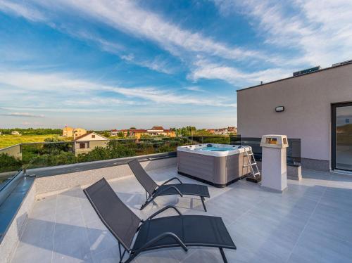 a patio with chairs and a hot tub on a roof at Villa Contessa in Privlaka