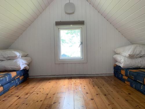 een zolderkamer met 2 bedden en een raam bij Tangloppen Camping & Cottages in Ishøj