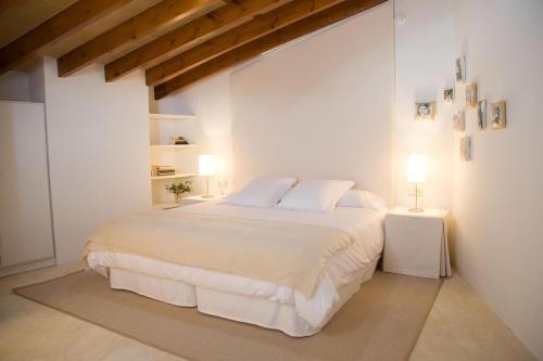 a white bedroom with a large bed and two lamps at S'Hotelet de Santanyi in Santanyi