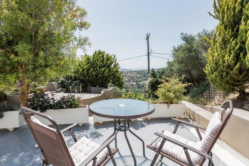 a patio with a table and chairs and trees at Knossos Palace Secluded Villa in Skalánion