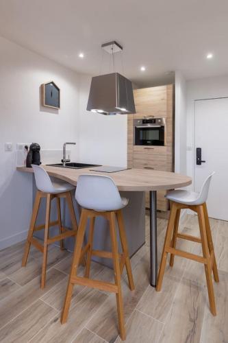 - une cuisine avec une table en bois et deux tabourets de bar dans l'établissement Superbe Appartement 5pers - 3km-8min DisneyLand, à Magny-le-Hongre