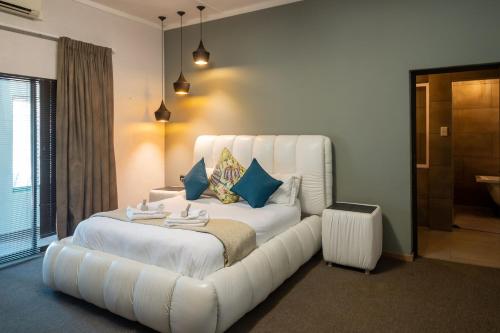 a bedroom with a large white bed with a white couch at Lala Dene Lodge in Bloemfontein