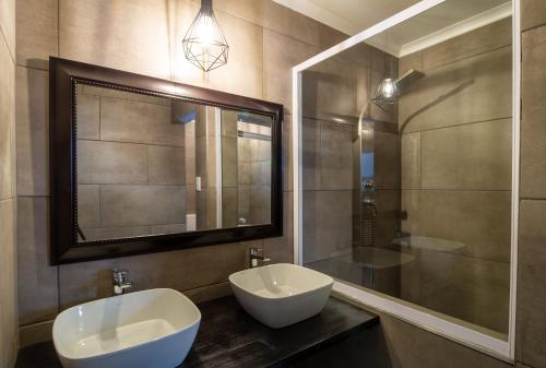 a bathroom with two sinks and a large mirror at Lala Dene Lodge in Bloemfontein