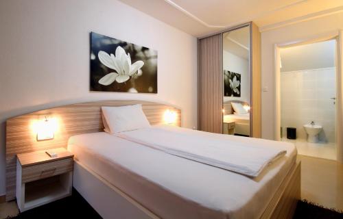 sypialnia z dużym białym łóżkiem i lustrem w obiekcie Hotel Aruba w Budvie