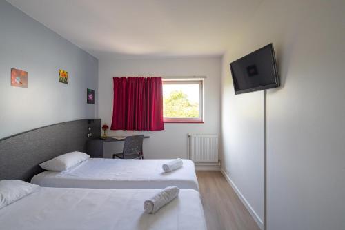 a hotel room with two beds and a flat screen tv at Hotel CIS Paris Kellermann in Paris