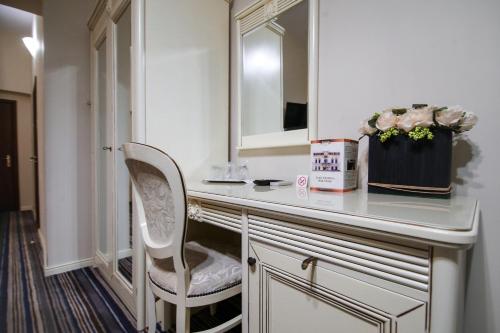 a bathroom with a vanity with a chair and a mirror at Hotel Royal Craiova in Craiova