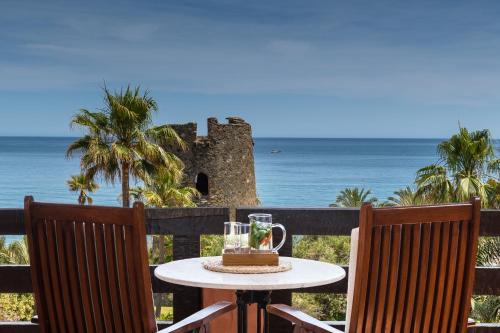 a table with a drink on a balcony with the ocean at Kempinski Hotel Bahía Beach Resort & Spa in Estepona