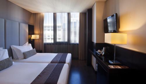 um quarto de hotel com duas camas e uma televisão de ecrã plano em TURIM Av. Liberdade Hotel em Lisboa