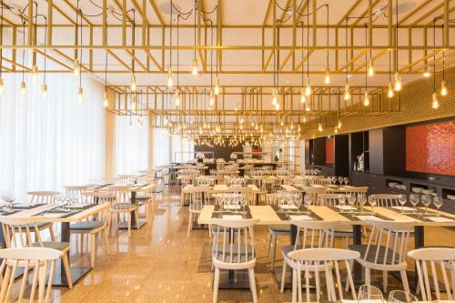 a dining room with tables and chairs and chandeliers at Hotel Estrela De Fatima in Fátima