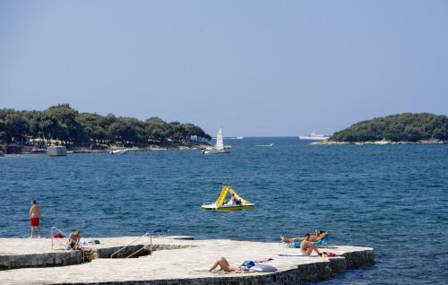 a group of people laying on the beach in the water at Victoria Mobilehome in Orsera Camping Resort in Vrsar