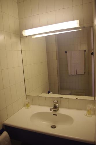 a bathroom with a sink and a large mirror at Hotel Belambra Le Normont in Dourdan