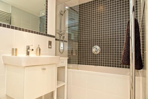 a white bathroom with a sink and a shower at Fowey Landing in Fowey