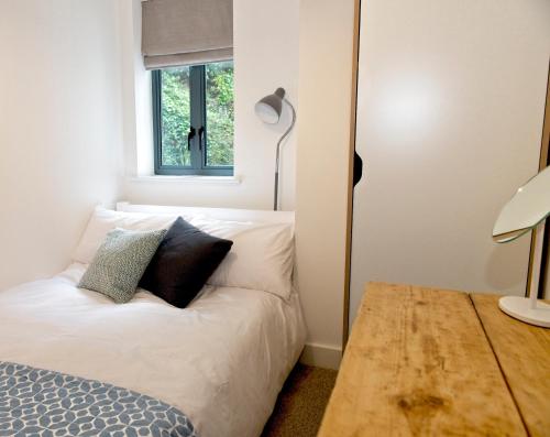 a bedroom with a white bed and a window at Fowey Landing in Fowey