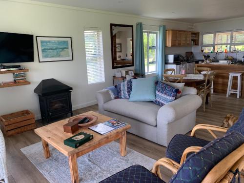 a living room with a couch and a table at Trinity Farm Ocean view Cottage in Plettenberg Bay