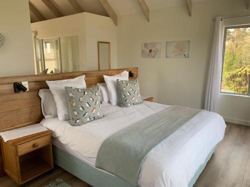 a bedroom with a large bed with white sheets and pillows at Trinity Farm Ocean view Cottage in Plettenberg Bay