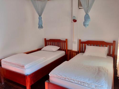 two twin beds in a room withthritisthritisthritisthritisthritisthritisthritisthritisthritis at Sunset Bungalows & GH in Ban Ngoy-Nua