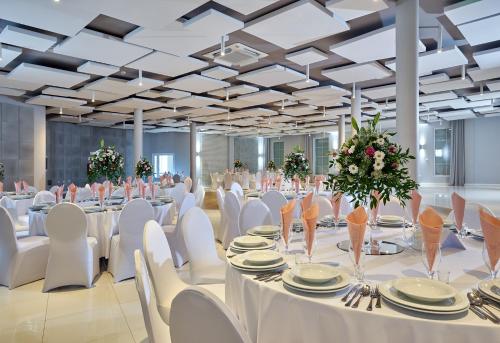 a large banquet hall with white tables and white chairs at Hotel Mużakowski in Łęknica