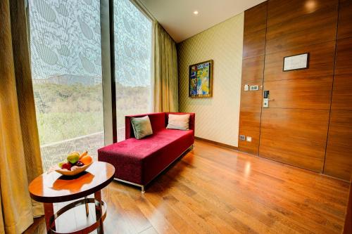 a living room with a red couch and a table at Niranta Transit Hotel Mumbai Airport - At Arrivals in Mumbai