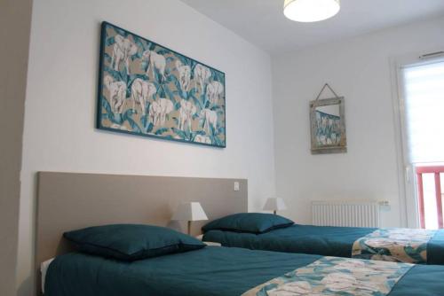 1 dormitorio con 2 camas y un cuadro en la pared en ZIBURU TERRASSE PARKING TOUT A PIED SAINT JEAN DE LUz, en Ciboure