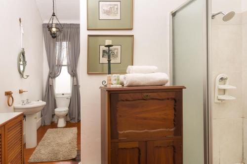 a bathroom with a sink and a toilet and a shower at Royston Hall Historical Guesthouse in Umtentweni