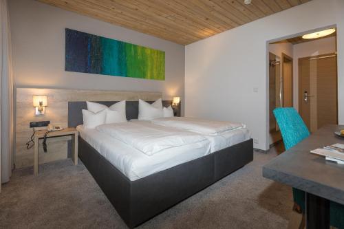 a bedroom with a large white bed and a table at KOSIS Sports Lifestyle Hotel in Fügen