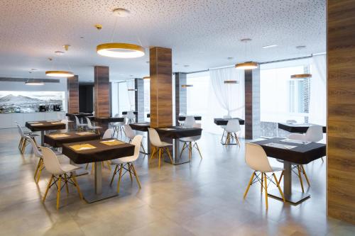 a restaurant with black tables and white chairs at Hotel Spa Calagrande Cabo de Gata in Las Negras